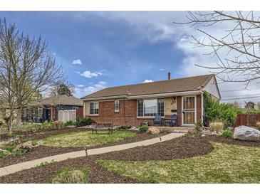 Charming brick home with a well-manicured front yard, inviting walkway, and cozy seating area at 3600 Olive St, Denver, CO 80207