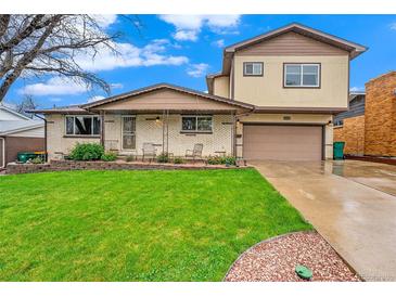 Inviting home featuring a well-maintained lawn, classic brickwork, and a cozy covered porch at 8871 Rutgers St, Westminster, CO 80031