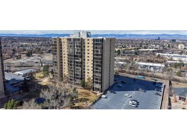 Modern high-rise building with large windows and an adjacent parking lot, set against a backdrop of city and mountains at 7865 E Mississippi Ave # 702, Denver, CO 80247