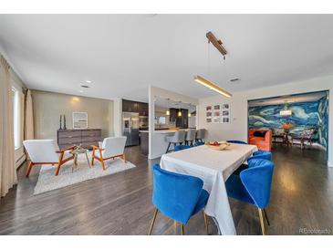 Bright living room featuring hardwood floors, stylish seating, and an open layout to the dining area and kitchen at 6630 E Virginia Ave, Denver, CO 80224