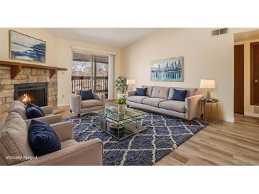 Bright living room features a stone fireplace, plush seating, and sliding door access to outdoor space at 3412 S Eagle St # 202, Aurora, CO 80014