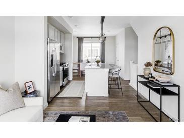 A modern, neutral kitchen flows into the dining area, featuring stainless steel appliances and a granite island with seating at 2862 S Galapago Ct, Englewood, CO 80110