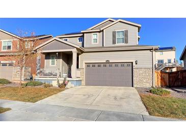 Charming two-story home featuring a gray exterior, well-maintained lawn, and inviting front porch at 9448 Richfield St, Commerce City, CO 80022
