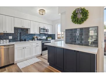 Modern kitchen featuring white cabinets, subway tile backsplash, stainless appliances, and stylish island at 3855 S Monaco St # 182, Denver, CO 80237