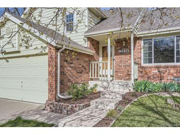 Inviting front entrance with brick accents, a light-colored exterior, and steps leading to the front door at 12036 Monaco Dr, Brighton, CO 80602