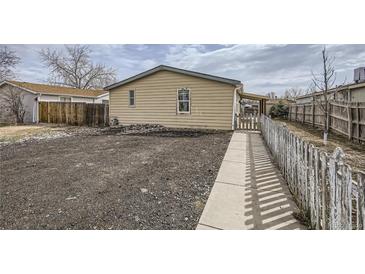 Exterior backyard featuring gravel, partial fencing, and small home elevation at 130 Elm St, Hudson, CO 80642