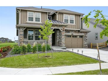 Beautiful two-story home featuring a stone facade, manicured lawn, and attached two car garage at 270 Maddox Ln, Erie, CO 80516