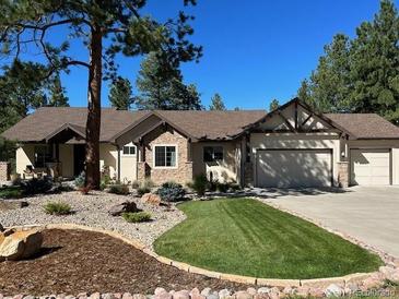 Charming single-story home featuring a well-manicured lawn and rock landscaping at 1151 Kenosha Dr, Larkspur, CO 80118