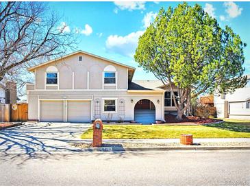 Charming two-story home features an attached two-car garage, well-maintained lawn, and mature trees at 8403 Chase Dr, Arvada, CO 80003