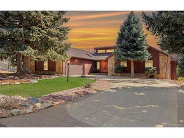 Charming home featuring stone accents, mature trees, a well-manicured lawn, and a spacious driveway at 7570 Windford, Parker, CO 80134