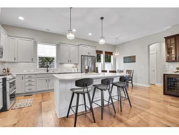 Bright kitchen with stainless steel appliances, white cabinets, quartz countertops, and an island with barstool seating at 8056 E 35Th Ave, Denver, CO 80238