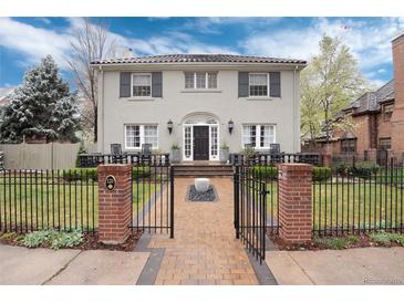 Two-story gray home featuring a black gated fence, front porch, and brick walkway leading to a black front door at 121 N Marion St, Denver, CO 80218