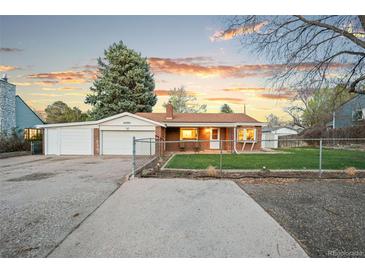 Charming brick home featuring a well-maintained front yard, long driveway and detached two car garage with a new door at 4550 S Fox St, Englewood, CO 80110