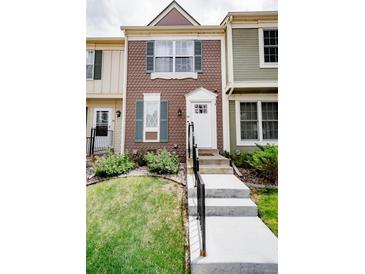Charming townhouse featuring a well-manicured lawn and inviting entryway with concrete stairs and black railings at 1699 S Trenton St # 69, Denver, CO 80231