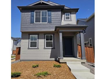 Charming two-story home with a covered porch, gray siding, and well-maintained landscaping at 2071 Generations Aly, Brighton, CO 80601