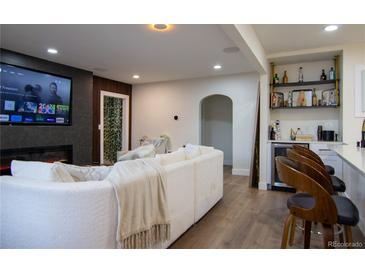 Comfortable living room with fireplace, large screen TV, and bar area with stools and shelves at 3701 S Grant St, Englewood, CO 80113