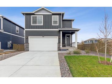 Charming two-story home boasts a two-car garage, a well-manicured lawn, and stone accents at 1813 Pinnacle Ave, Lochbuie, CO 80603