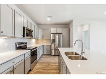 Modern kitchen with stainless steel appliances, light gray cabinets, and quartz countertops at 485 Interlocken Blvd # 202, Broomfield, CO 80021