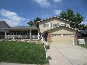 Charming two-story home with a well-manicured lawn, covered porch, and attached two-car garage at 12931 W Florida Dr, Lakewood, CO 80228