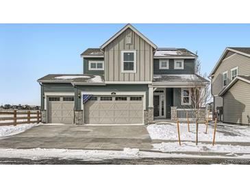 Two-story house with gray siding, beige garage doors, and a snowy front yard at 185 Baler Ct, Brighton, CO 80601