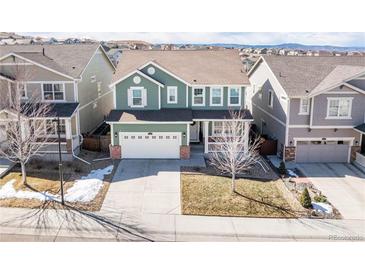 Two-story home featuring a two-car garage, front porch, and green siding at 2541 Leafdale Cir, Castle Rock, CO 80109