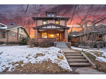 Brick two-story home with snow-covered lawn and steps leading to the entrance at 1149 Steele St, Denver, CO 80206