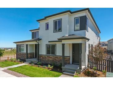 Charming two-story townhome with stone accents, a well-manicured lawn, and a welcoming covered front porch at 14125 Deertrack Ln, Parker, CO 80134