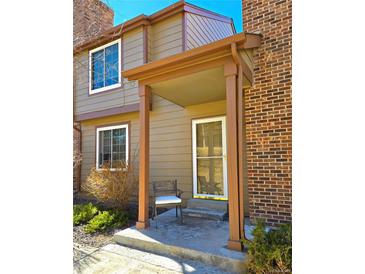 Charming front entrance with a cozy porch, a chair, and a combination of brick and siding at 886 Summer Dr, Highlands Ranch, CO 80126