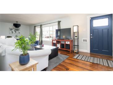 Inviting living room featuring hardwood floors, a large window, and a comfortable seating area at 2401 E 35Th Ave, Denver, CO 80205