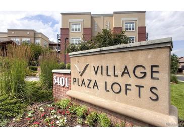 Village Plaza Lofts building signage with manicured landscaping, tall grasses, and the community building in the background at 5401 S Park Terrace Ave # 204C, Greenwood Village, CO 80111