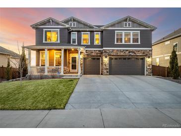 Inviting two-story home with a covered front porch, stone accents, and an attached two-car garage at 1825 Wingfeather Ln, Castle Rock, CO 80108