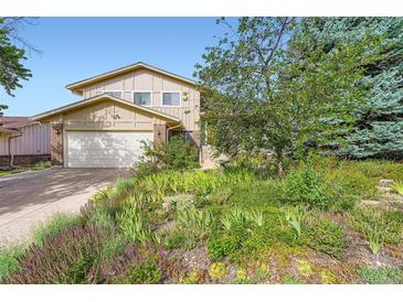 Two-story home featuring an attached garage and complemented by a vibrant and beautifully landscaped front yard at 13934 W Warren Dr, Lakewood, CO 80228