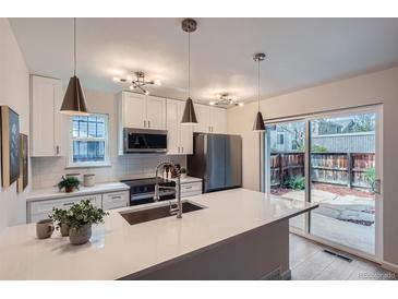 Bright kitchen features white cabinets, stainless appliances, large island, and access to the backyard at 1251 S Yosemite Way # 92, Denver, CO 80247