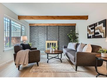 Cozy living room featuring a brick fireplace, wood beams, and modern furnishings at 1251 S Yosemite Way # 92, Denver, CO 80247