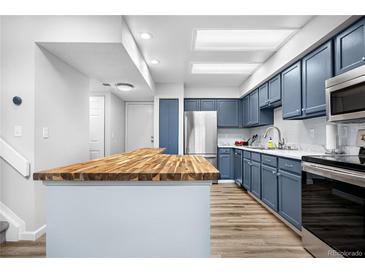 Bright kitchen featuring stylish blue cabinets, stainless steel appliances, and butcher block breakfast bar at 4301 S Pierce St # 6D, Littleton, CO 80123