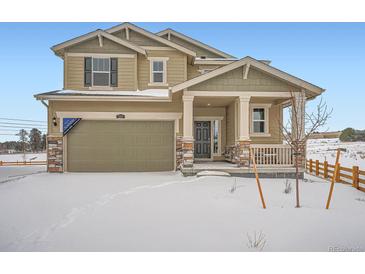 Two-story house with a green exterior, a large garage, and snowy landscaping at 210 Paloma Way, Elizabeth, CO 80107