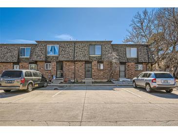 Three-unit townhouse exterior showing brick facade and parking spaces in front on a sunny day at 14462 E Mississippi Ave # B, Aurora, CO 80012