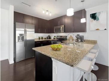 This kitchen features sleek, dark cabinetry, stainless steel appliances, and granite countertops with a breakfast bar at 1062 Rockhurst Dr # 302, Highlands Ranch, CO 80129