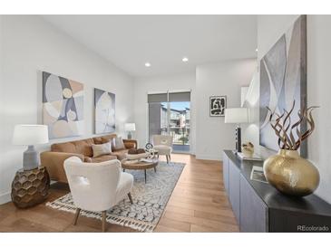 Bright living room features wood floors, neutral paint, and a sliding glass door to a balcony at 7812 W 43Rd Pl, Wheat Ridge, CO 80033