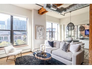 Bright living room featuring exposed ductwork, large windows, and stylish modern furnishings at 1720 Wynkoop St # Ph403, Denver, CO 80202