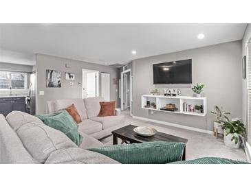 Cozy living room featuring a comfortable sectional sofa, mounted TV, and stylish shelving unit at 2268 S Laredo St, Aurora, CO 80013