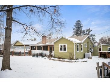 Charming single-story home with a brick chimney, adjacent carport, and a spacious snow-covered yard at 1205 Lee St, Lakewood, CO 80215