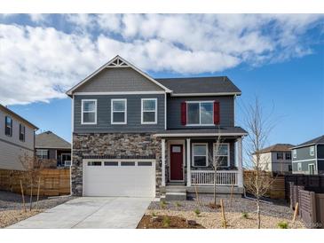 Charming two-story home with a stone facade, red door and shutters, and attached two-car garage at 14269 Beebalm Ave, Parker, CO 80134