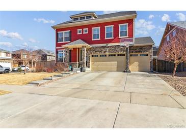 Charming two-story home with red siding, stone accents, a three-car garage, and a well-maintained front yard at 4736 S Buchanan St, Aurora, CO 80016