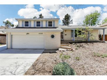 Charming home featuring a white brick exterior, two-car garage, and meticulous landscaping at 14582 E Harvard Ave, Aurora, CO 80014