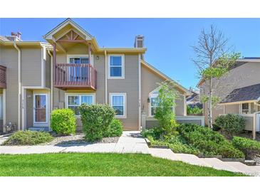 Two-story townhouse with tan siding, second story balcony, mature landscaping, and walkway at 4146 S Mobile Cir # A, Aurora, CO 80013