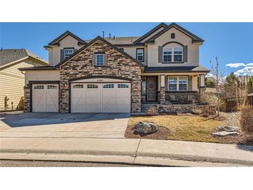 Inviting two-story home with a three car garage, stone accents, and a manicured lawn at 2702 Rising Moon Way, Castle Rock, CO 80109