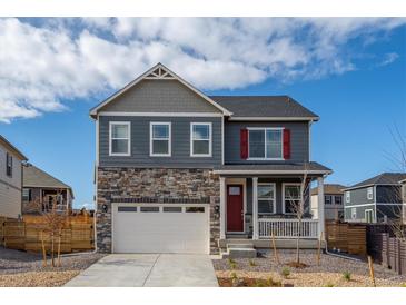 Charming two-story home with a stone facade, white garage door, and red front door at 27664 E Byers Ave, Aurora, CO 80018