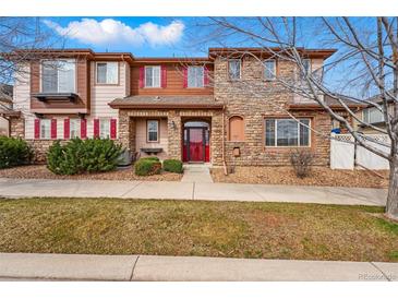 Inviting exterior of a townhome featuring stone and siding, a red front door, and tidy landscaping at 11307 Navajo Cir # A, Westminster, CO 80234