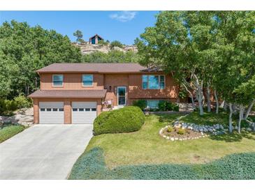 Charming two-story home featuring a well-manicured lawn, mature trees, and a two-car garage at 452 Gordon Dr, Castle Rock, CO 80104